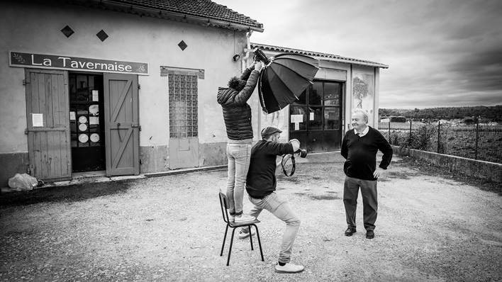 Photographe prenant le portrait d'un homme en noir et blanc avec lumière professionnelle