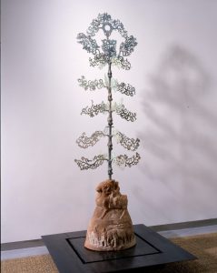 arbre à monnaies asiatiques en métal sur socle de pierre beige et fond gris