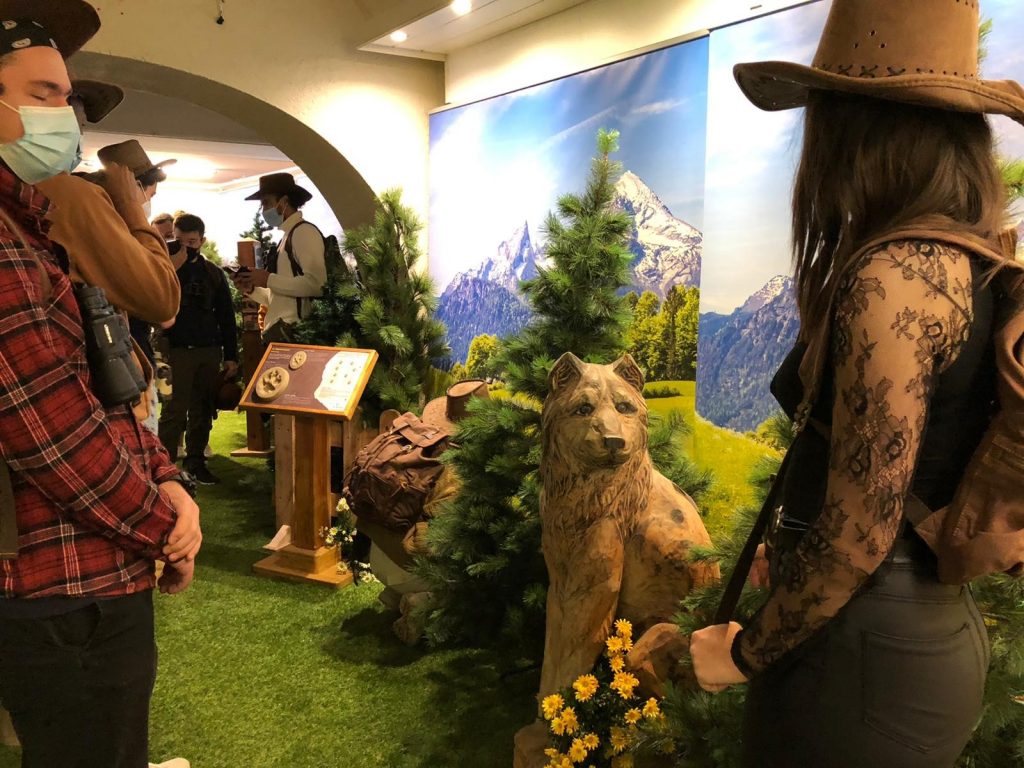 Jeunes masqués devant sculpture en bois de loup